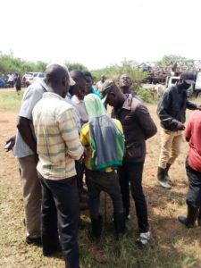 Ugandan cattle keepers and buyers surrounding a drone pilot during a flight demonstration